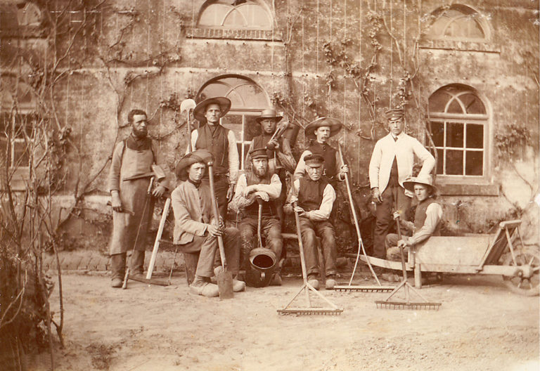 Oude foto in sepia kleuren van een groep mannen voor het huis Landfort.