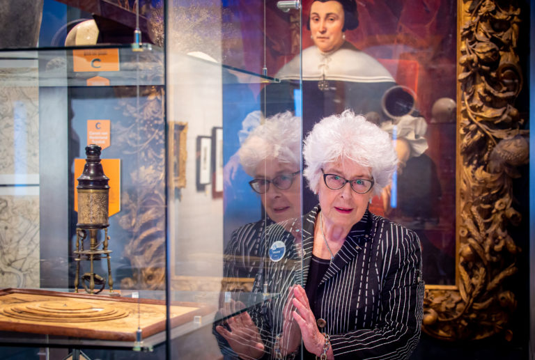 Portret van erfgoedvrijwilliger Trude bij een display van het MuZeeum