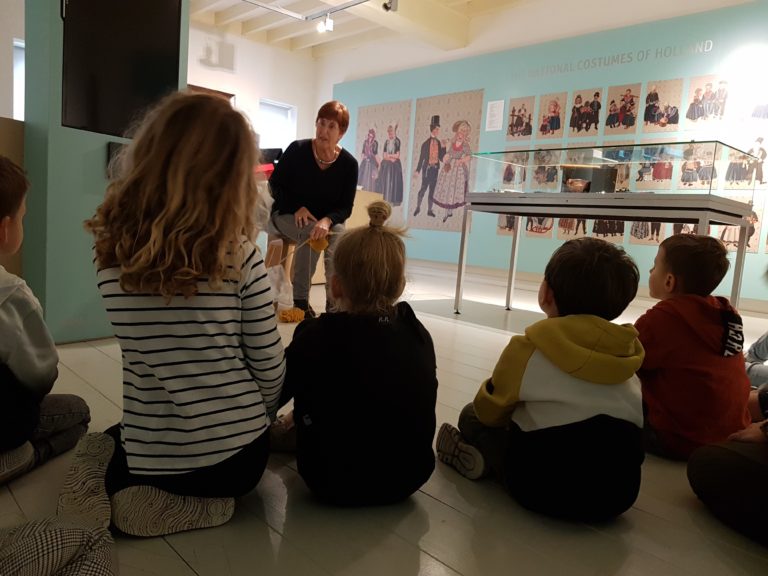 Vrijwilliger museum vertelt iets aan jonge kinderen