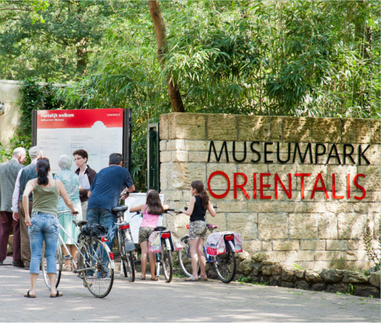 Bezoekers op de fiets bij de ingang van Museumpark Orientalis