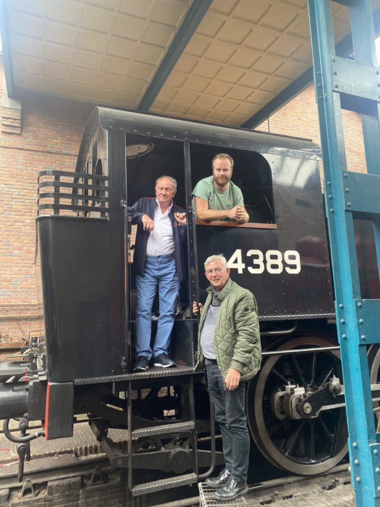 Portret van drie erfgoedvrijwilligers bij en in een zwart treinstelletje