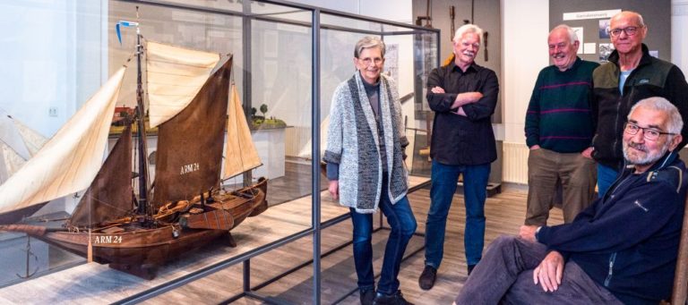 Vrijwiligers van museum Arnemuiden bij een historisch model van een zeilschip
