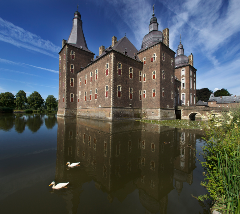 Kasteel Hoensbroek, op de voorgrond de slotgracht waarin het kasteel weerspiegeld is en twee witte eenden.
