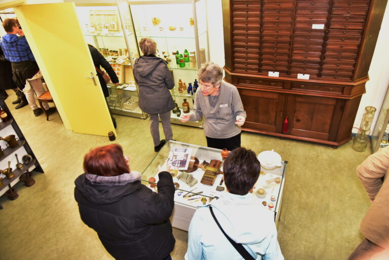 Twee bezoekers krijgen uitleg van een vrijwilliger in het museum.