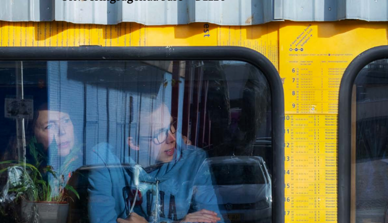 Twee mensen kijken uit het raam van een kunstwerk dat lijkt op een trein van de NS
